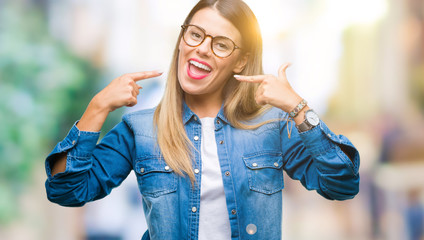 Young beautiful woman over wearing glasses over isolated background smiling confident showing and pointing with fingers teeth and mouth. Health concept.