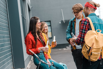 happy friends with bicycle drinking beer from bottles on street