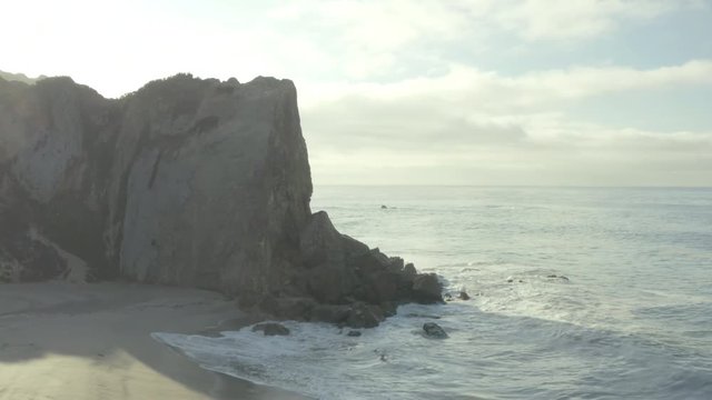 Aerial fly around of a cliff on the beach.