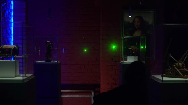 Young man and a woman with flashlights are trying to make robbery a gallery protected by laser alarms