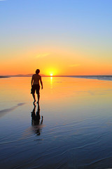 Fototapeta premium Young man walking on the beach at sunset time