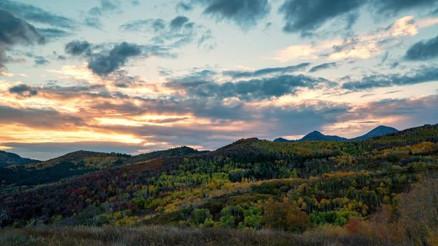 Time lapse of sun setting over mountain layers viewing colorful landscape during Fall.