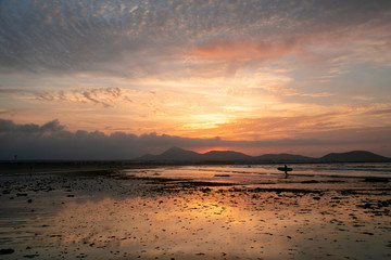 Fototapeta na wymiar Amazing sunset with pockmarked sky shot on a sandy beach at low tide
