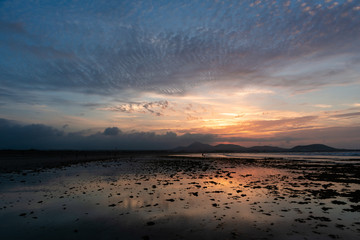 Amazing sunset with pockmarked sky shot on a sandy beach at low tide
