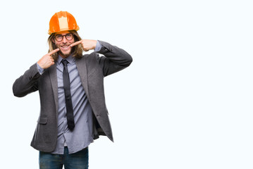 Young handsome architec man with long hair wearing safety helmet over isolated background smiling confident showing and pointing with fingers teeth and mouth. Health concept.