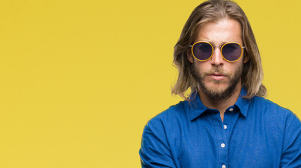 Young handsome man with long hair wearing sunglasses over isolated background skeptic and nervous, disapproving expression on face with crossed arms. Negative person.