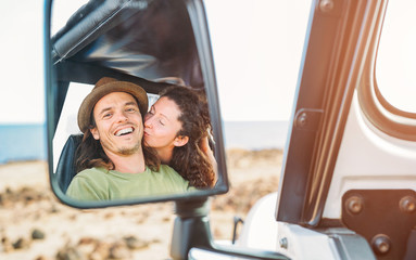Happy couple having a tender moment during their road trip with a convertible car - Pov in a car...