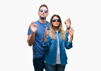 Young couple in love wearing sunglasses over isolated background relax and smiling with eyes closed doing meditation gesture with fingers. Yoga concept.