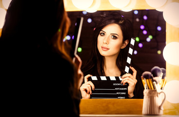 portrait of young beautiful woman with slapstick looking in the mirror