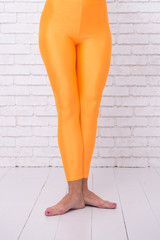 dancing ballet position of feet. orange. practicing in ballet studio. sport wear fashion. woman in...