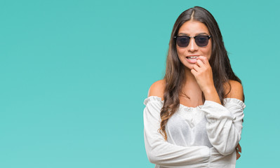 Young beautiful arab woman wearing sunglasses over isolated background looking stressed and nervous with hands on mouth biting nails. Anxiety problem.