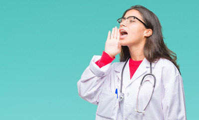 Young arab doctor woman over isolated background shouting and screaming loud to side with hand on mouth. Communication concept.