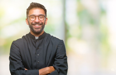 Adult hispanic catholic priest man over isolated background happy face smiling with crossed arms looking at the camera. Positive person. - obrazy, fototapety, plakaty
