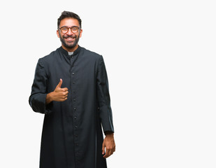 Adult hispanic catholic priest man over isolated background doing happy thumbs up gesture with...