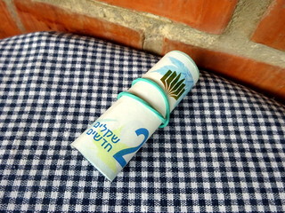 Israeli sheqel in tube on a checkered background