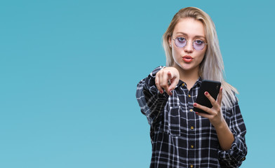 Young blonde woman texting sending message using smartphone over isolated background pointing with...