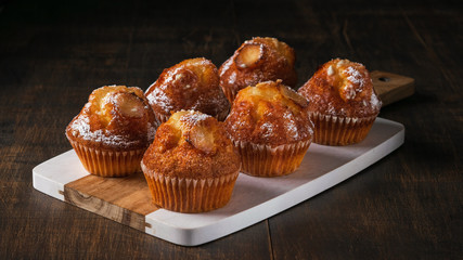 Freshly baked vanilla muffins with sugar powder, served on wooden board. Horizontal. Top view. Copy space, Dark Background Banner. Close-up.