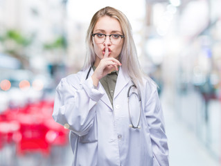 Young blonde doctor woman over isolated background asking to be quiet with finger on lips. Silence and secret concept.