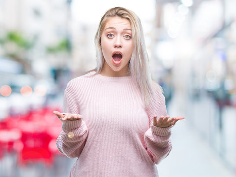 Young blonde woman wearing winter sweater over isolated background afraid and shocked with surprise expression, fear and excited face.