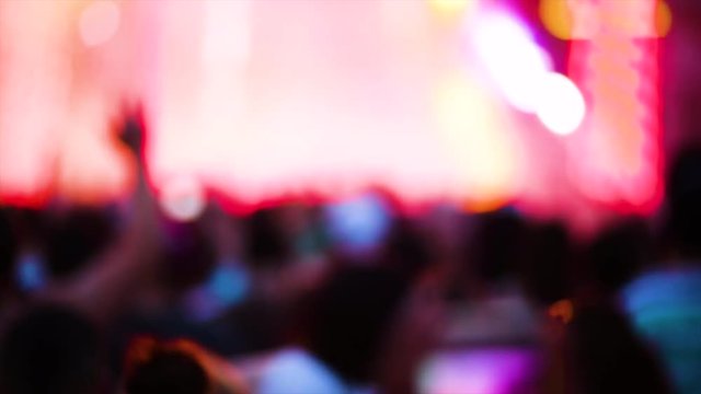 A Concert Goer uses their cell phone to record videos of an electronic music festival from the back of the crowd.