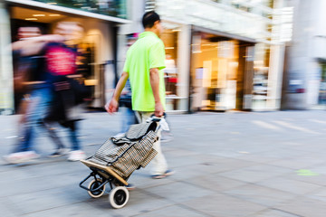 man with a shopping trolley on a shopping street