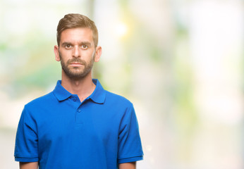 Young handsome man over isolated background with serious expression on face. Simple and natural looking at the camera.