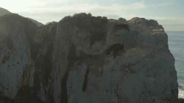 Aerial ascending shot and fly over of a cliff on the beach.