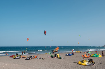 Many kitesurfer and windsurfer on ocean at surfer beach El Medano, Tenerife