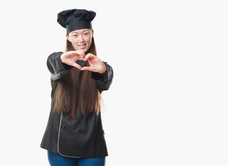 Young Chinese woman over isolated background wearing chef uniform smiling in love showing heart...