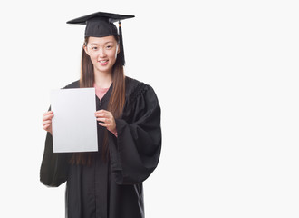 Young Chinese woman wearing graduate uniform holding paper degree with a happy face standing and smiling with a confident smile showing teeth