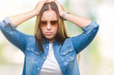 Young beautiful caucasian woman wearing sunglasses over isolated background suffering from headache desperate and stressed because pain and migraine. Hands on head.