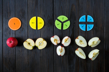 colorful math fractions and apples as a sample on brown wooden background or table. interesting...