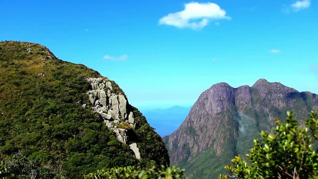 view of open landscape from a mountain side and another mountain with foliage in the foreground, peak Paran&radic;&deg;, South Brazil on August 19, 2018.