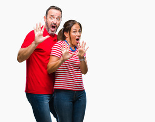 Obraz premium Middle age hispanic couple in love over isolated background afraid and terrified with fear expression stop gesture with hands, shouting in shock. Panic concept.