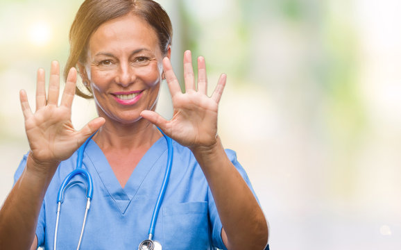 Middle age senior nurse doctor woman over isolated background showing and pointing up with fingers number ten while smiling confident and happy.