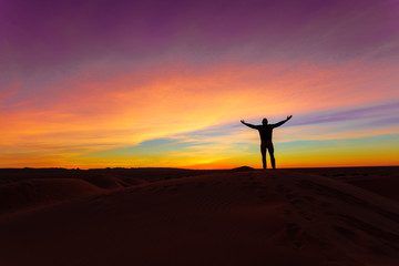 Silhouette of man posing on sand dune during the sunset