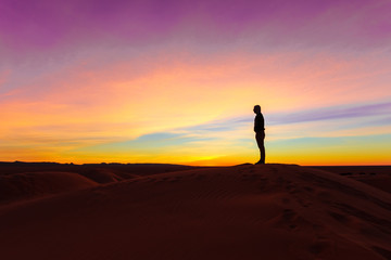 Fototapeta na wymiar Silhouette of man posing on sand dune during the sunset