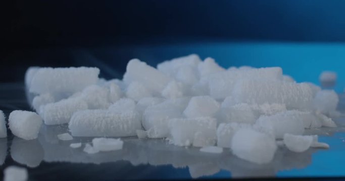 Dry Ice Pellets on glass in front of dark blue background