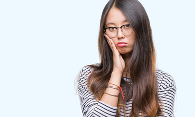 Young asian woman wearing glasses over isolated background thinking looking tired and bored with depression problems with crossed arms.