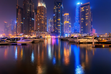 Fototapeta na wymiar Beautiful view to Dubai Marina, UAE. Luxury yachts at pier. Long exposure time lapse effect at night