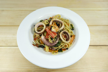 Spaghetti seafood in a white dish on a wood floor table,Top view copy space..