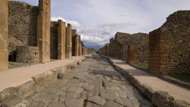 Narrow stone street leads through the ruins of Pompeii, Italy