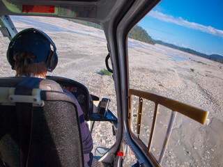 Helicopter cockpit view over broad river bed