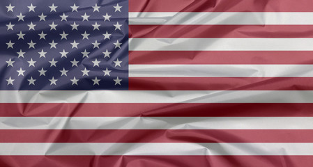 Obraz premium Fabric flag of United States of America. Crease of USA flag background, horizontal stripes of red and white with fifty white stars on a blue field.