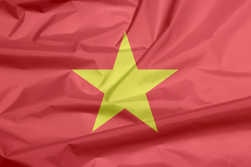 Fototapeta premium Fabric flag of Vietnam. Crease of Vietnamese flag background, yellow star on red flag.