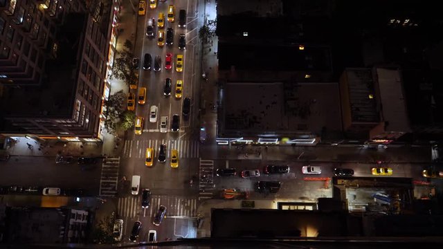A high angle nighttime view of a typical midtown Manhattan intersection as traffic and pedestrians travel on the streets below. Day/night matching available.  	