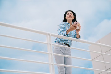 an elegant woman standing outdoor with a blue sky