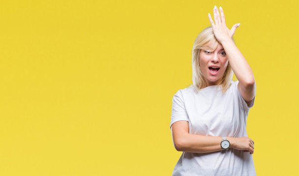 Young beautiful blonde woman wearing white t-shirt over isolated background surprised with hand on head for mistake, remember error. Forgot, bad memory concept.
