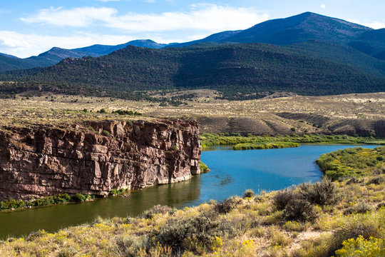 The Green River passes red-brown rock cliffs, wetlands, wide prairies, and mountains in Browns Park National Wildlife Refuge in northwestern Colorado