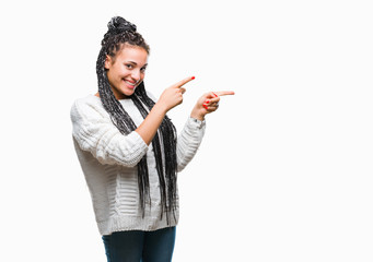 Young braided hair african american girl wearing sweater over isolated background smiling and looking at the camera pointing with two hands and fingers to the side.